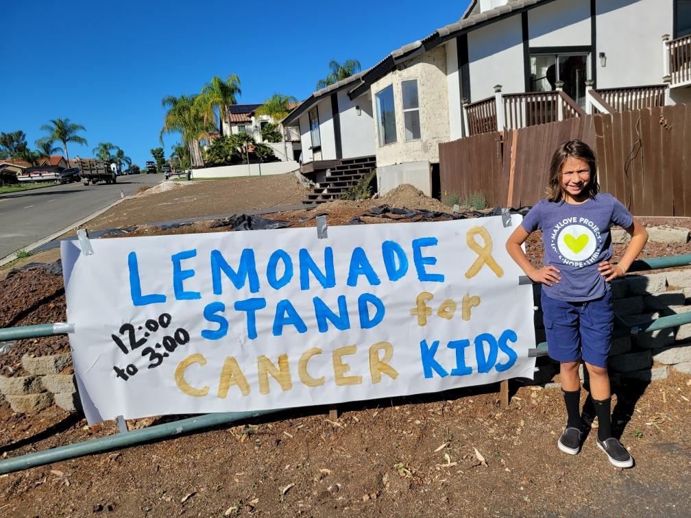 Girl standing in front of lemonade stand sign